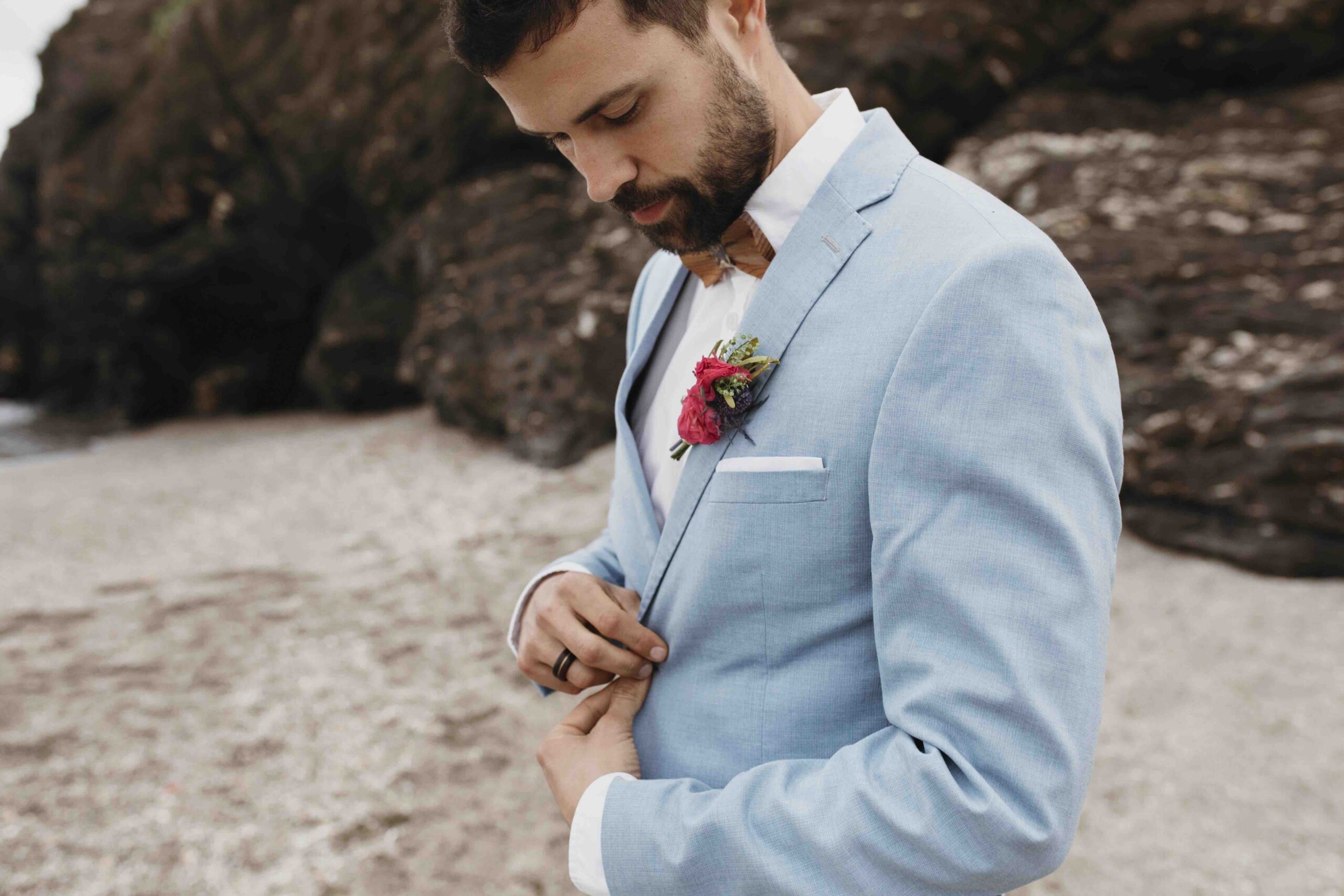 un homme sur la plage avec une fleur dans la poche en costume de mariage 